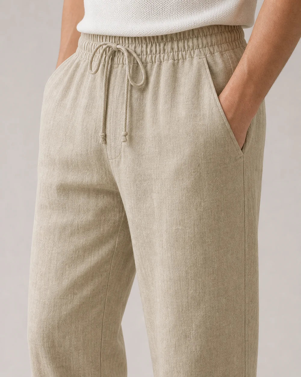 Close-up of beige linen pants elastic waistband, drawcord, pockets and fabric.